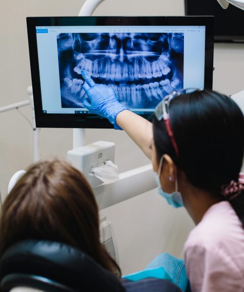 Dentist examines dental x-ray with patient in modern clinic setting.